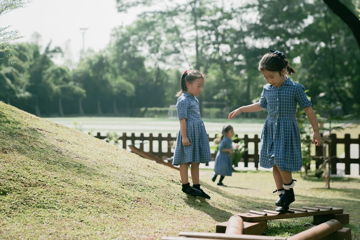 Pupils playing on the grass bank beside the school field