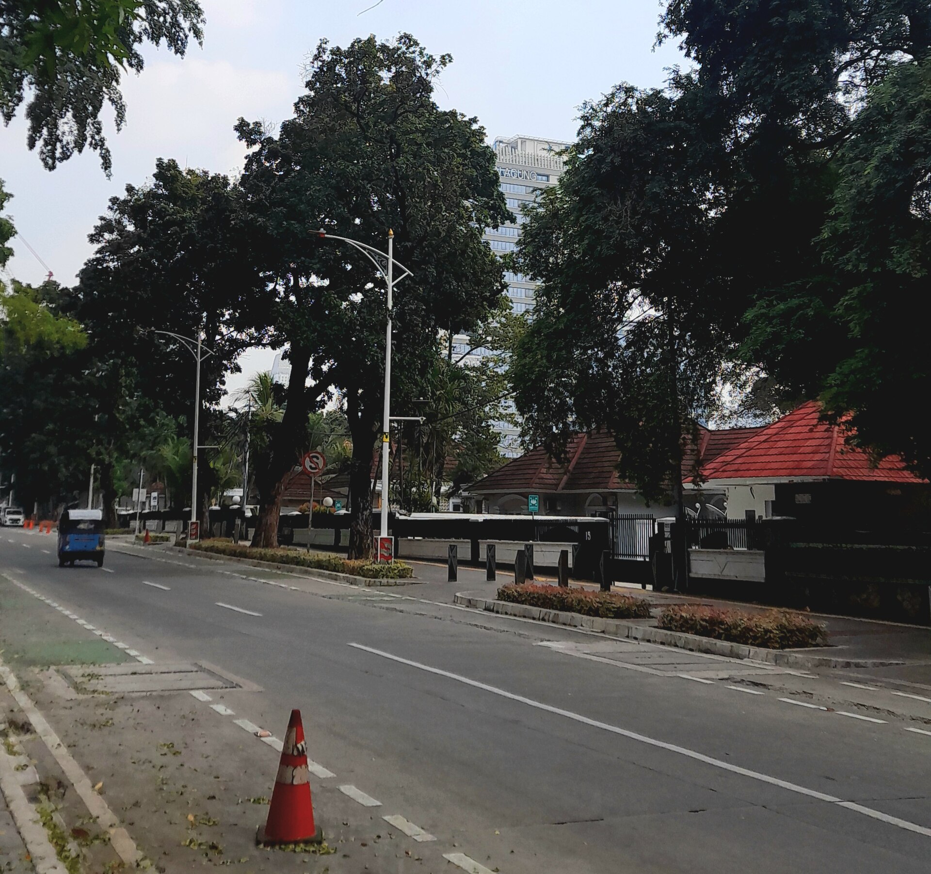 Tree-lined residential street in Kebayoran Baru, South Jakarta, with gated houses and cars