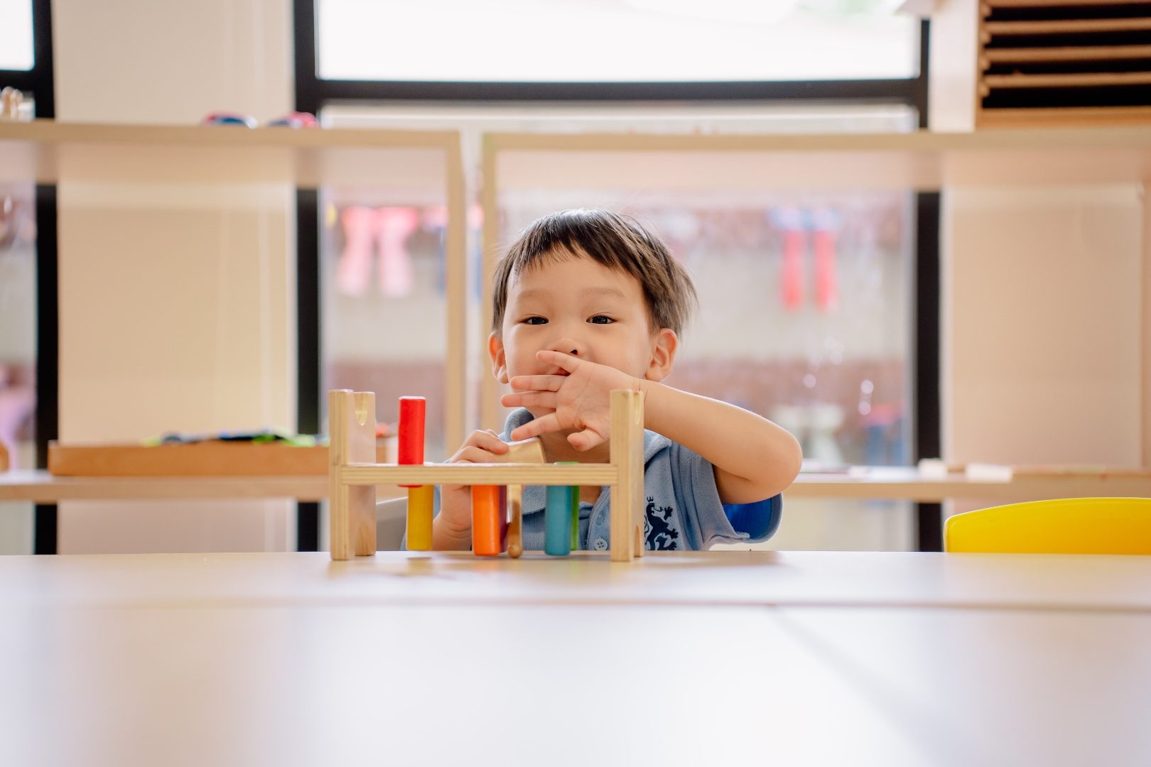 A young child working with a wooden peg toy in an early years classroom at ISJ Jakarta